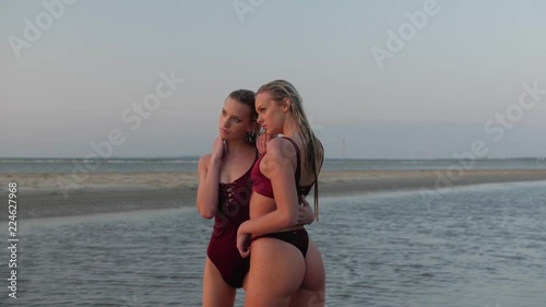 Two gorgeous blonde models posing at the beach in bikini suits photo