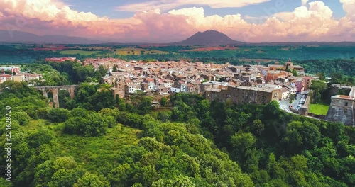 4k An aerial view of the town of Civita Castellana in Italy, pink cloudy sky and green trees and grass