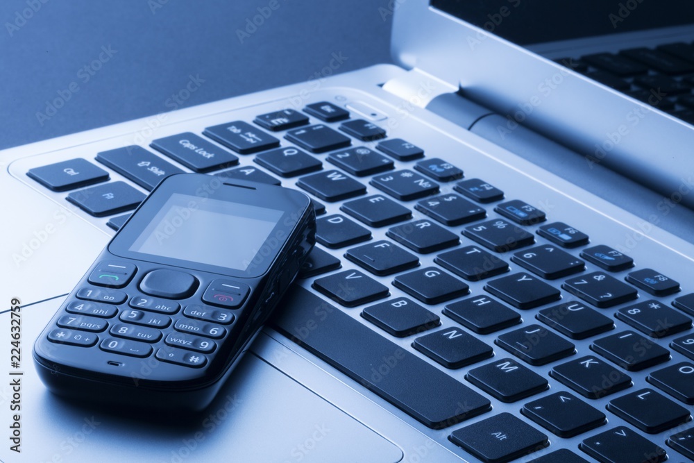 mobile phone on top of a laptop mobile phone on top of a laptop
