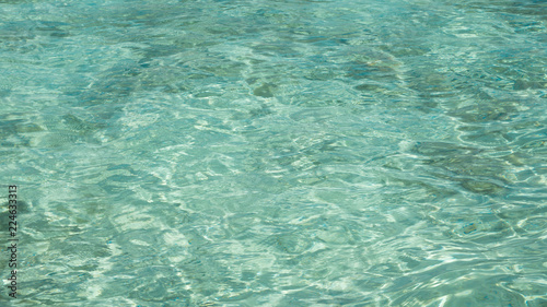 a clear and transparent blue green sea with shallow water and sun reflection