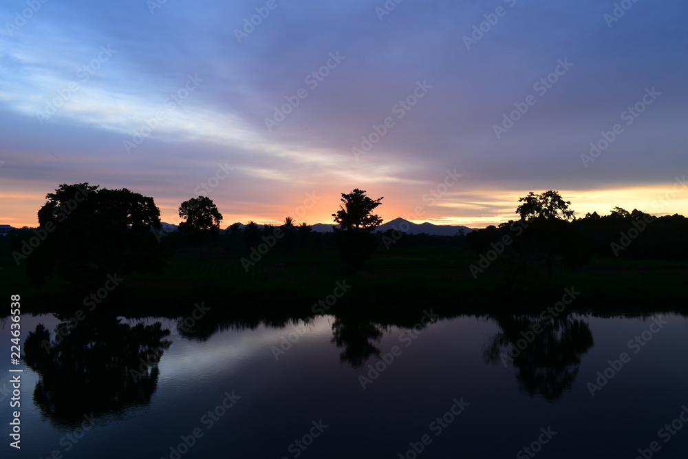 Time laps cloud flowing at sunset and silhouette of tree reflect in water 