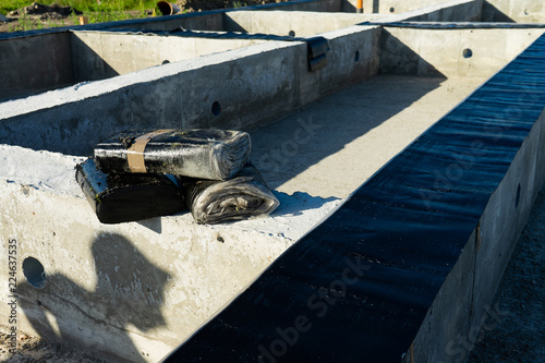 Workers carry out waterproofing of the Foundation for the construction of a wooden house.