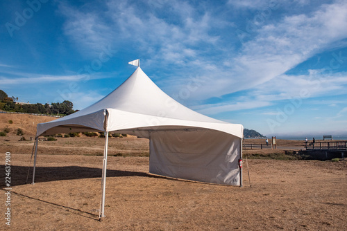 White tent in brown grass field under blue sky