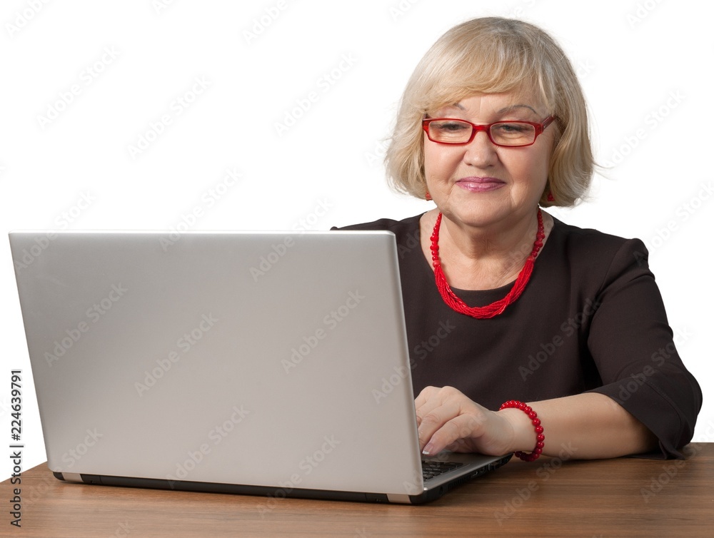 Friendly Old Woman Sitting behind Table and Typing on a Laptop - Friendly Old Woman Sitting behind Table and Typing on a Laptop -
