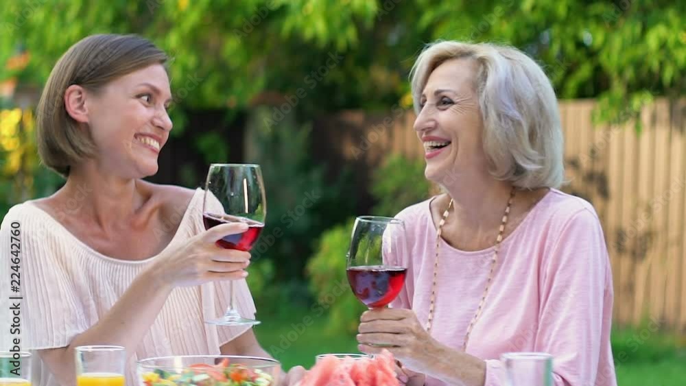 Daughter and mother-in-law pleasantly communicating outdoors with glass of wine Daughter and mother-in-law pleasantly communicating outdoors with glass of wine