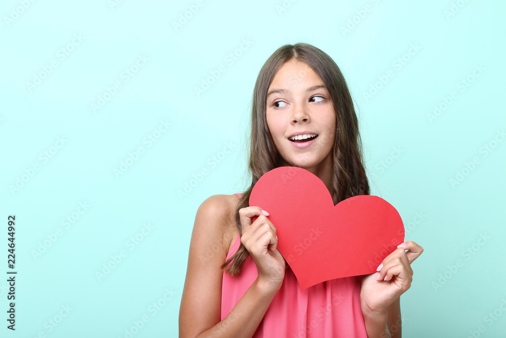 Young girl holding red paper heart on mint background Young girl holding red paper heart on mint background