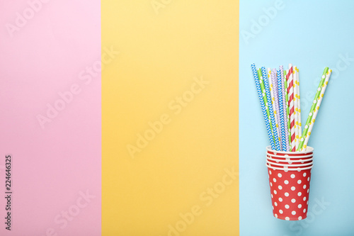 Red paper cups with straws on colorful background
