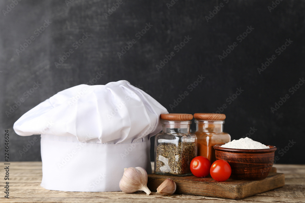 Chef hat with vegetables and spices in jars on wooden table Chef hat with vegetables and spices in jars on wooden table