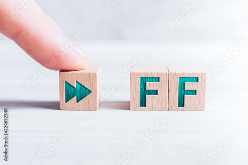 The Abbreviation FF Formed By Wooden Blocks And Arranged By A Male Finger On A White Table photo