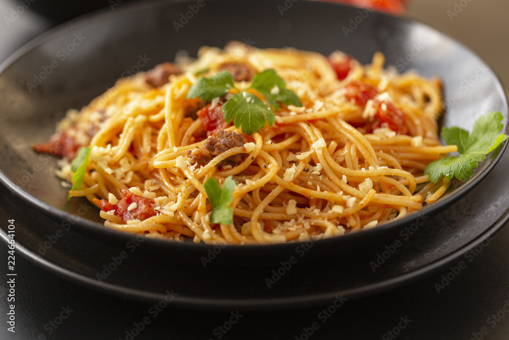 Delicious spaghetti with Bolognese sauce served on a black plate Delicious spaghetti with Bolognese sauce served on a black plate