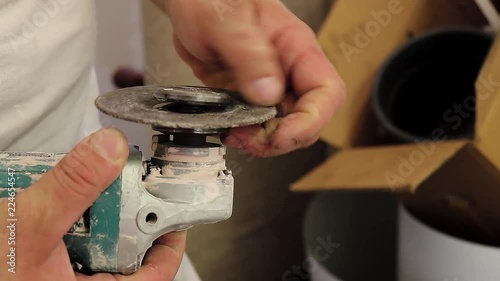 Man installing grinder disc, taking a new one out of backet and changing grinder disk to another, with handheld camera movement shake photo