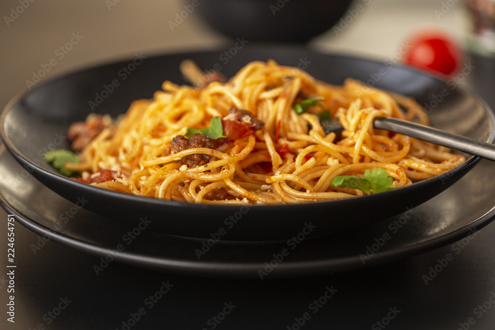 Delicious spaghetti with Bolognese sauce served on a black plate Delicious spaghetti with Bolognese sauce served on a black plate