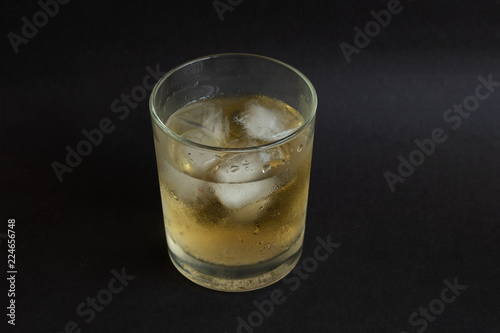 A glass of whisky with ice cubes on black color table background. Alcoholism. Party. 