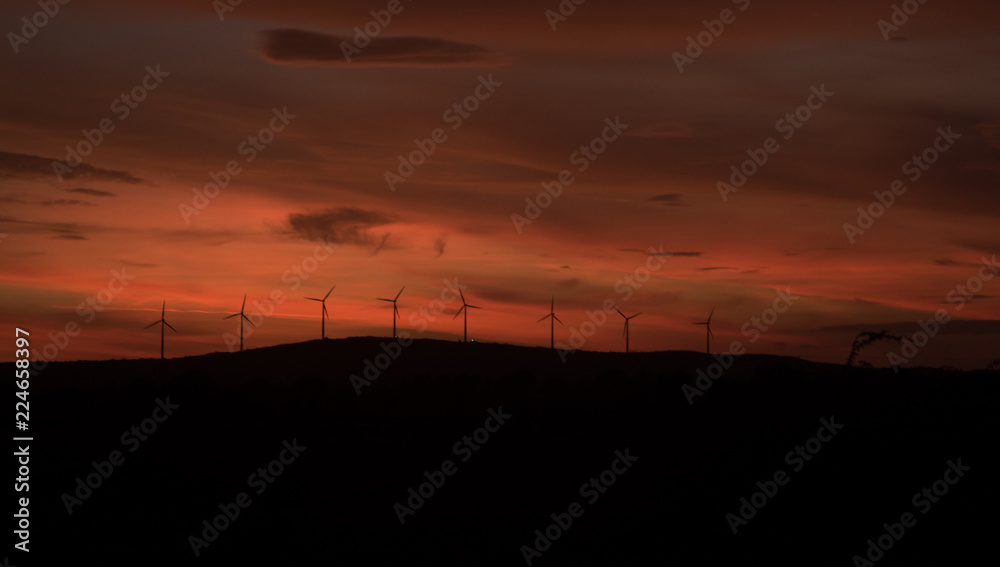 Wind Turbines On Hill At Sunset