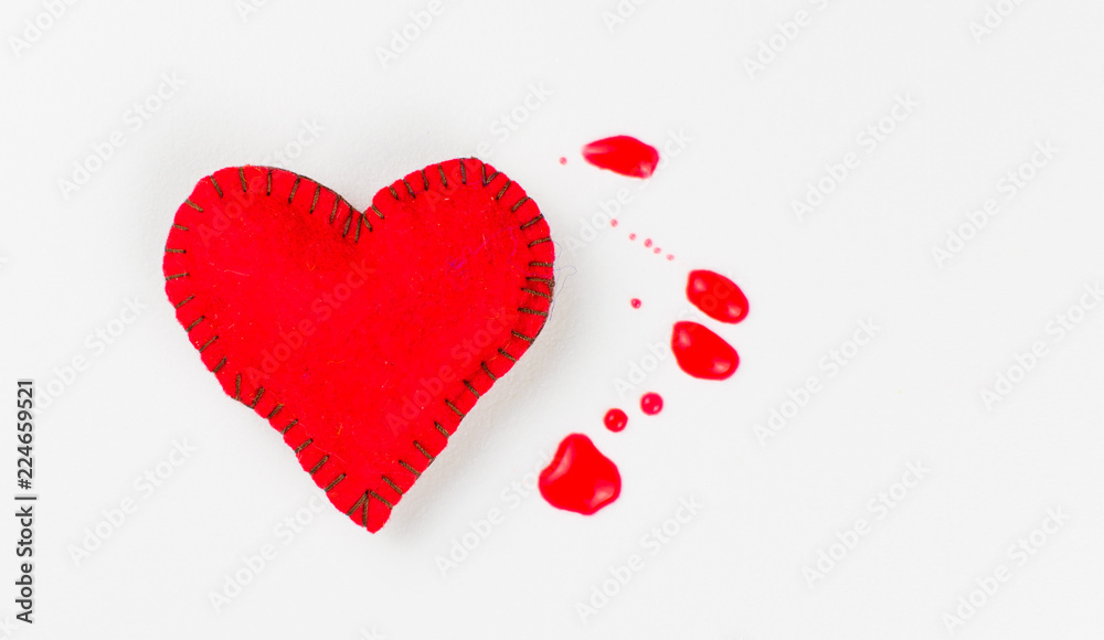 The concept of a bleeding heart. Stitched heart and blood spots on a white background. The concept of a bleeding heart. Stitched heart and blood spots on a white background.