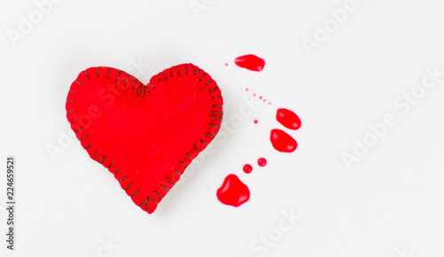 The concept of a bleeding heart. Stitched heart and blood spots on a white background.