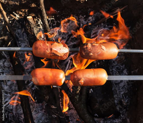 Delicious sausages roasting on an open fire in air