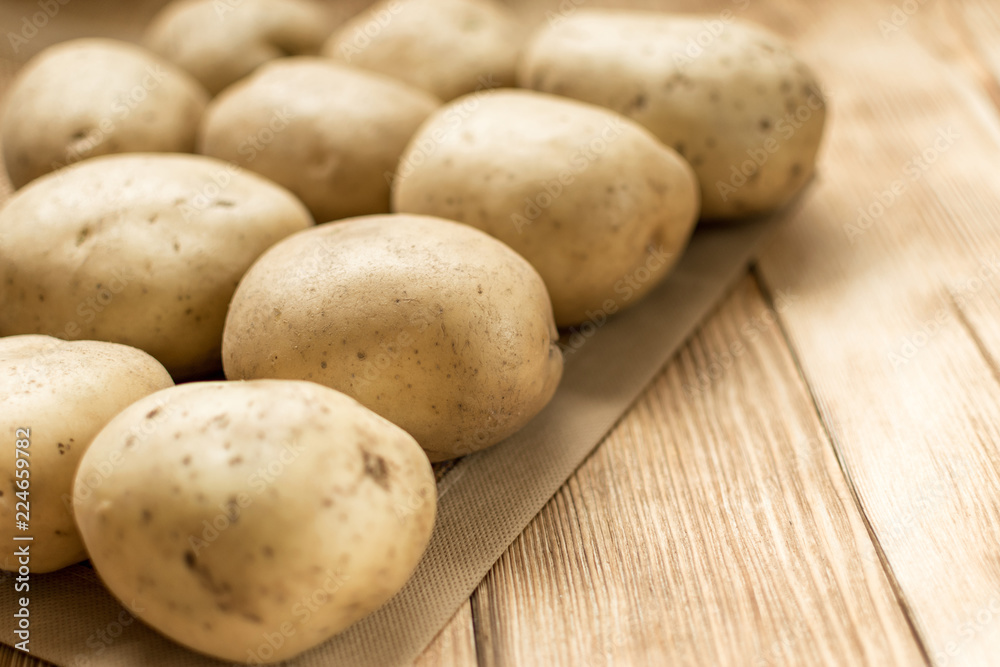 Raw potato tubers on a wooden background. Raw potato tubers on a wooden background.