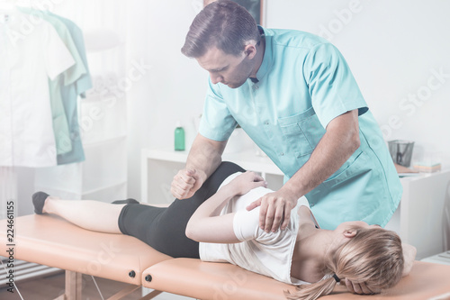 Doctor in uniform massaging patient with pain during physiotherapy
