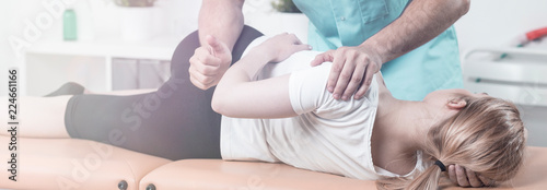 Panorama of physiotherapist massaging woman with pain of spine during rehabilitation
