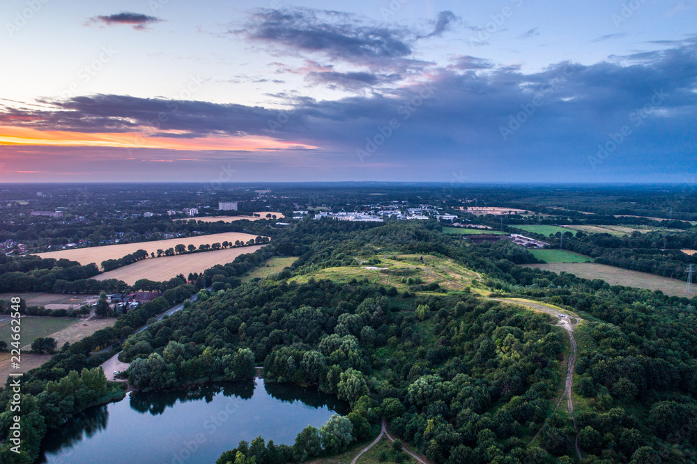Aerial view of amazing sunset over the park in Germany. Hill and lake from birds eye view.  