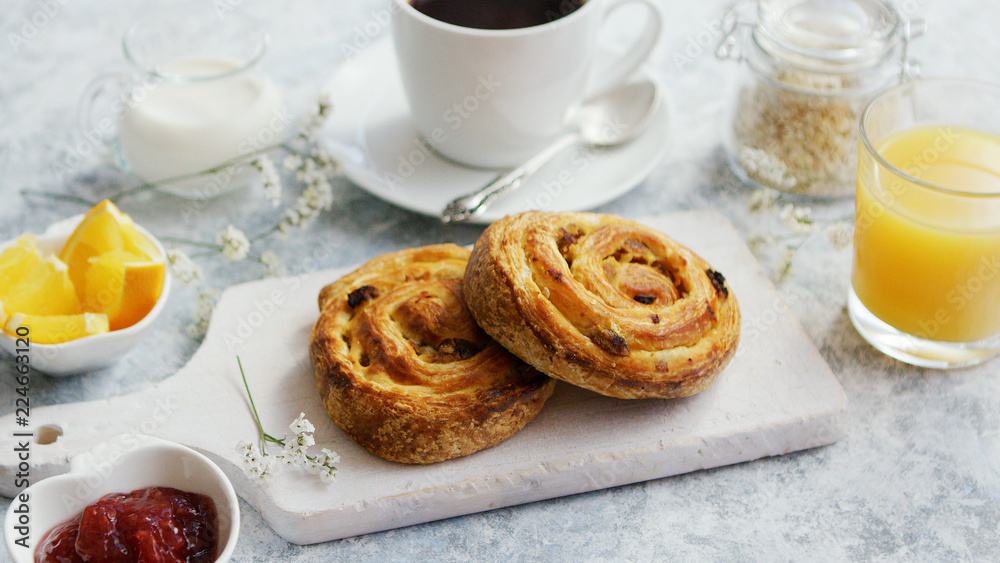 Served delicious breakfast meal with baked buns on wooden board on marble table with coffee and juice and jam Served delicious breakfast meal with baked buns on wooden board on marble table with coffee and juice and jam