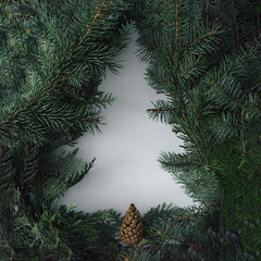 Negative space Christmas tree concept. Creative winter layout made with evergreen tree branches. Flat lay.