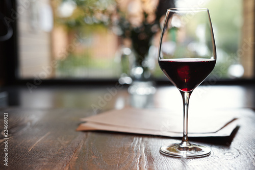 A Glass of red wine in restaurant or cafe on wooden table in front of window, romantic date, lunch relaxation