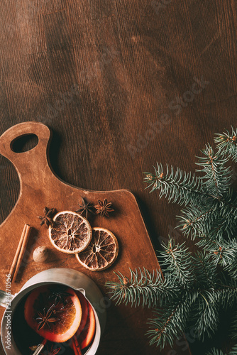 top view of hot homemade mulled wine with spices on cutting board on wooden background with fir branch