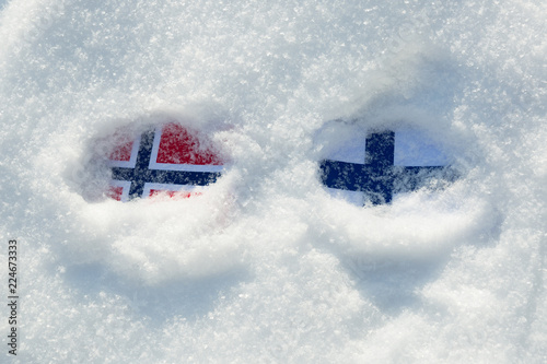 Fototapeta Naklejka Na Ścianę i Meble -  Flags of Norway and Finland buried in the snow.