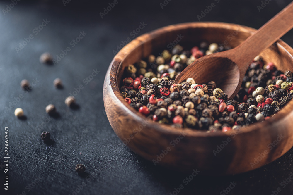close-up view of wooden bowl and spoon with dried aromatic peppercorns on black close-up view of wooden bowl and spoon with dried aromatic peppercorns on black