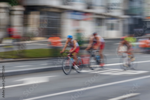 Blurred silhouettes of bicyclists on a blurred city background