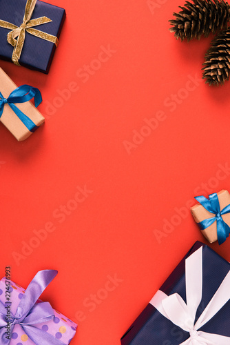 top view of christmas presents and pine cones on red background