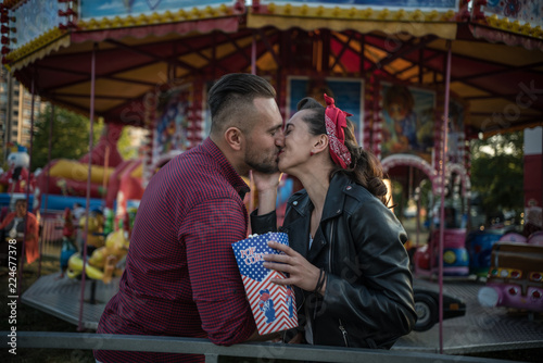 young cute couple in amusement park kissing 