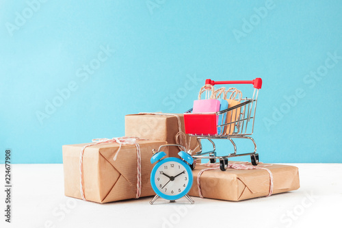 Internet shop / e-commerce sale and delivery service concept: shopping cart multicolored packages and boxes with trolleybus logo on laptop keyboard, blue background