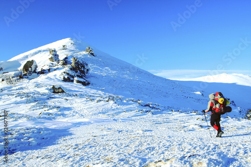 Winter hike in the mountains with a backpack and tent.