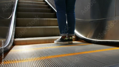 Close shot of electric escalator with parts of a person going upwards 