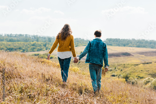 back view of couple walking on rural meadow