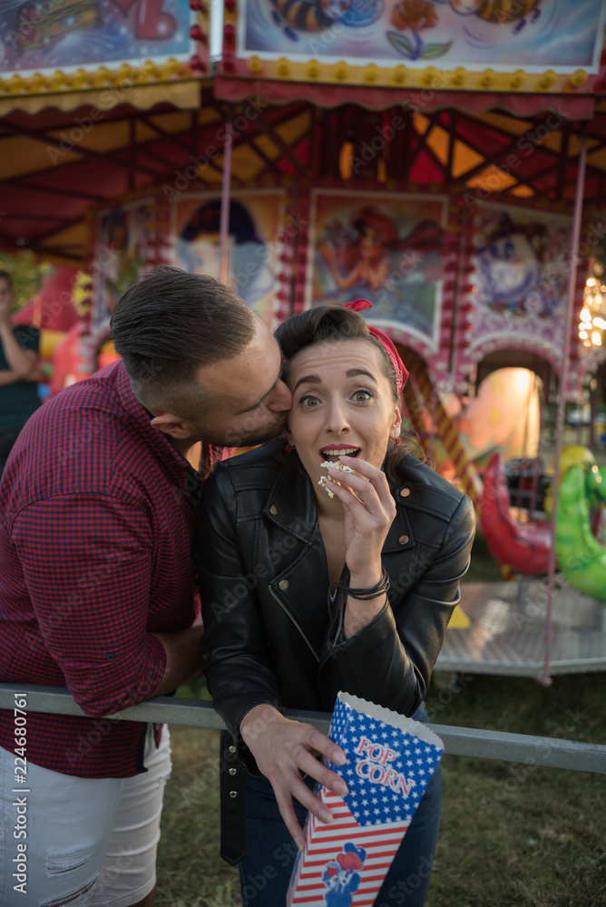 Obraz premium young cute couple in amusement park eating pop corns 