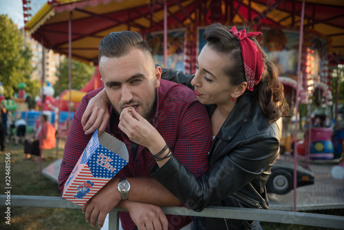 young cute  couple in amusement  park eating pop corns 