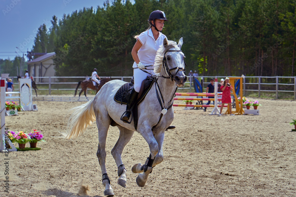 Young woman jockey in white dress and black boots, takes part in equestrian competitions. Close-up. Young woman jockey in white dress and black boots, takes part in equestrian competitions. Close-up.