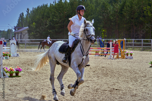 Young woman jockey in white dress and black boots, takes part in equestrian competitions. Close-up.
