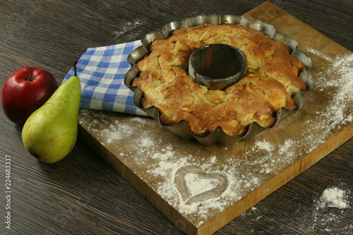 Homemade apple pie with a knitted cloth on wooden table