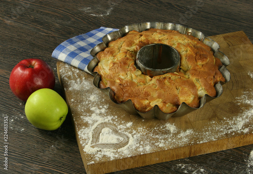 Homemade apple pie with a knitted cloth on wooden table