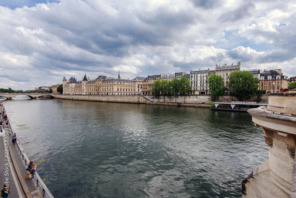 Paris, France - August 16, 2017. View of Seine river embankment, Cite island with Conciergerie Palace and Prison from oldest parisian bridge Pont Neuf.