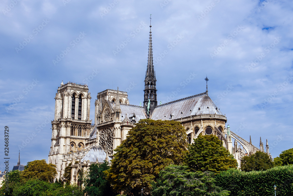 Paris, France - August 13, 2017. View of medieval Notre Dame de Paris Cathedral, masterpiece of Gothic architecture and most visited monument in France with green trees in front. Paris, France - August 13, 2017. View of medieval Notre Dame de Paris Cathedral, masterpiece of Gothic architecture and most visited monument in France with green trees in front.
