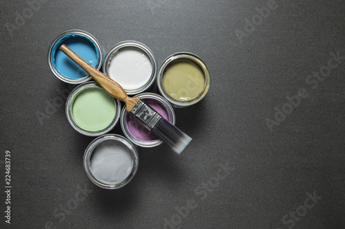 Pastel paint tins and brush on grey marble surface.