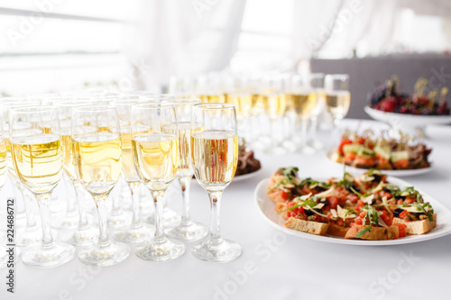 Lot of glasses champagne or wine on the table in restaurant. buffet table with lots of delicious snacks. © malkovkosta