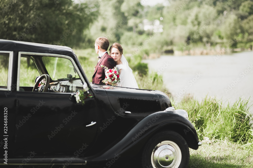 Stylish wedding couple, bride, groom kissing and hugging on retro car Stylish wedding couple, bride, groom kissing and hugging on retro car
