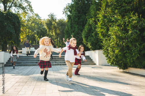 Funny starts. Kids fashion concept. The group of teen boys and girls running at park. Children colorful clothes, lifestyle, trendy colors concepts.